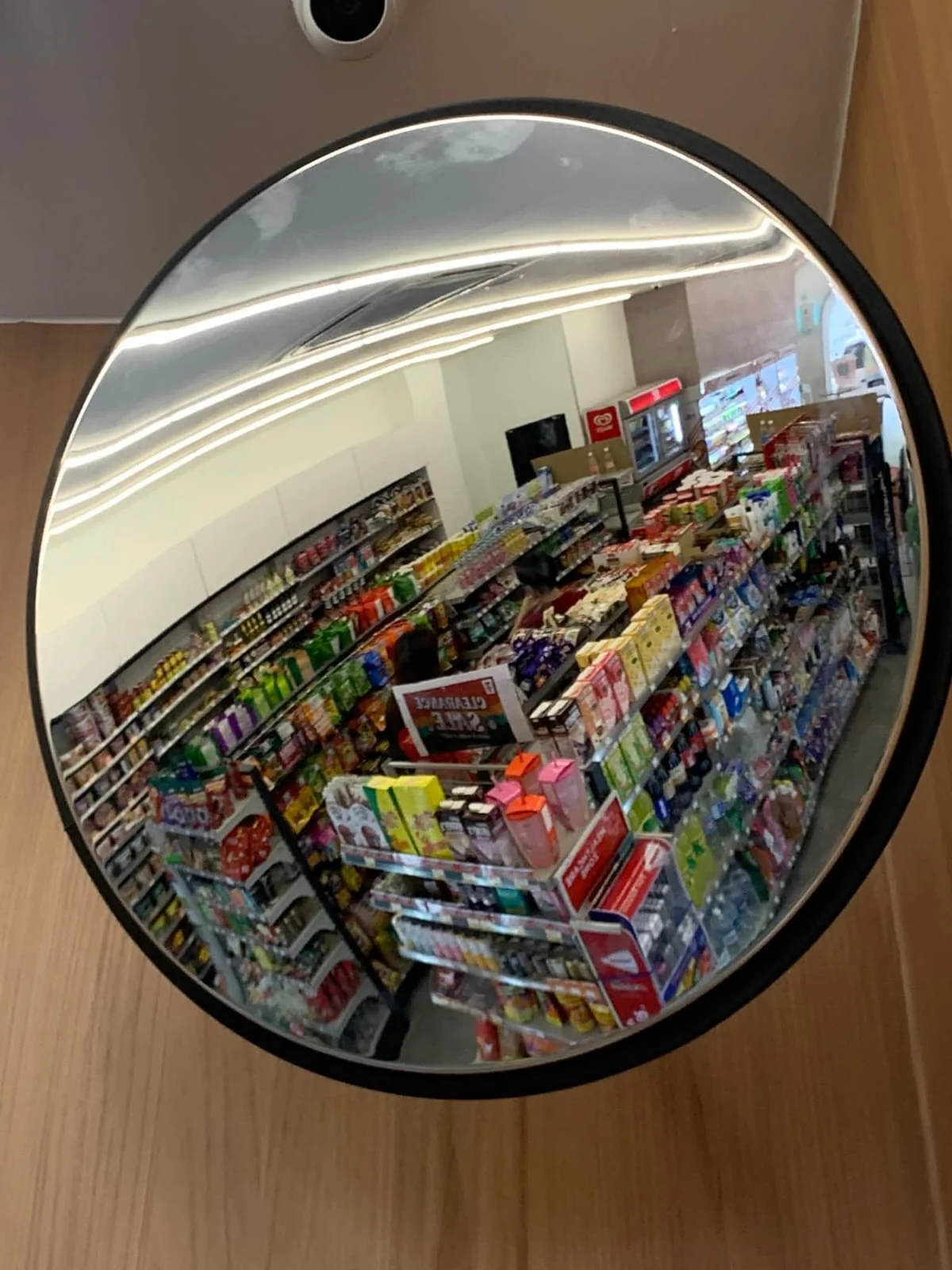 Specchio convesso circolare con bordo nero installato all’interno di un supermercato.