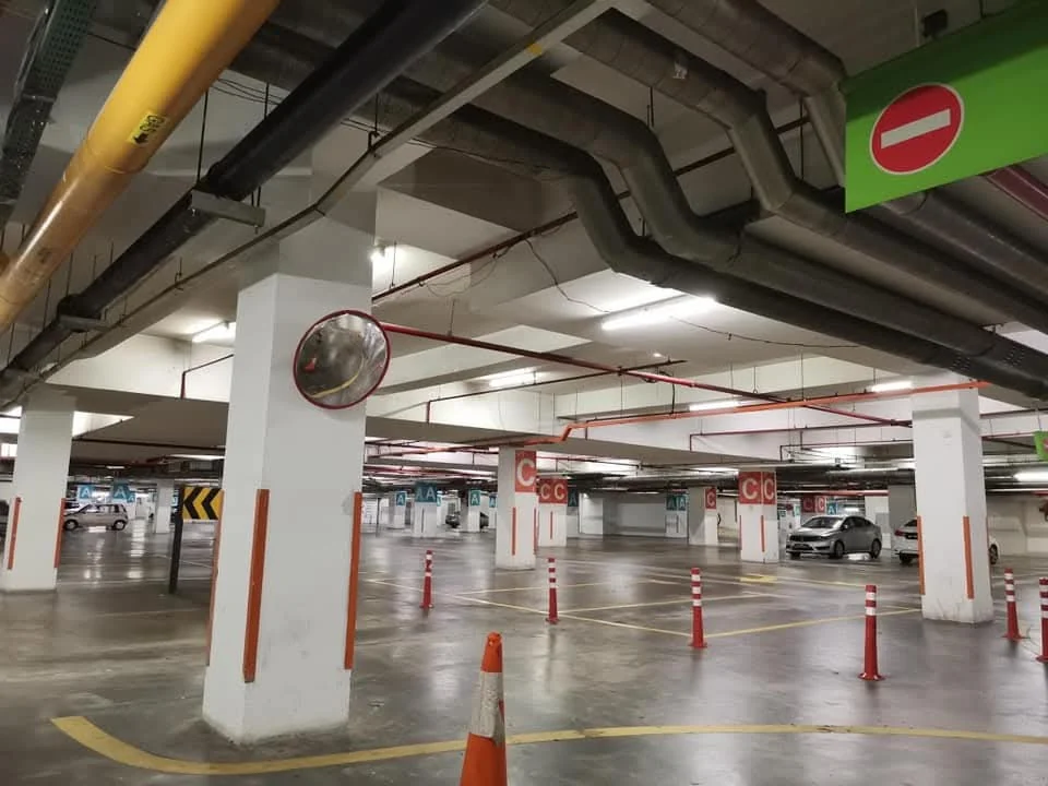 Specchio convesso montato su una colonna in un parcheggio coperto con corsie e stalli.